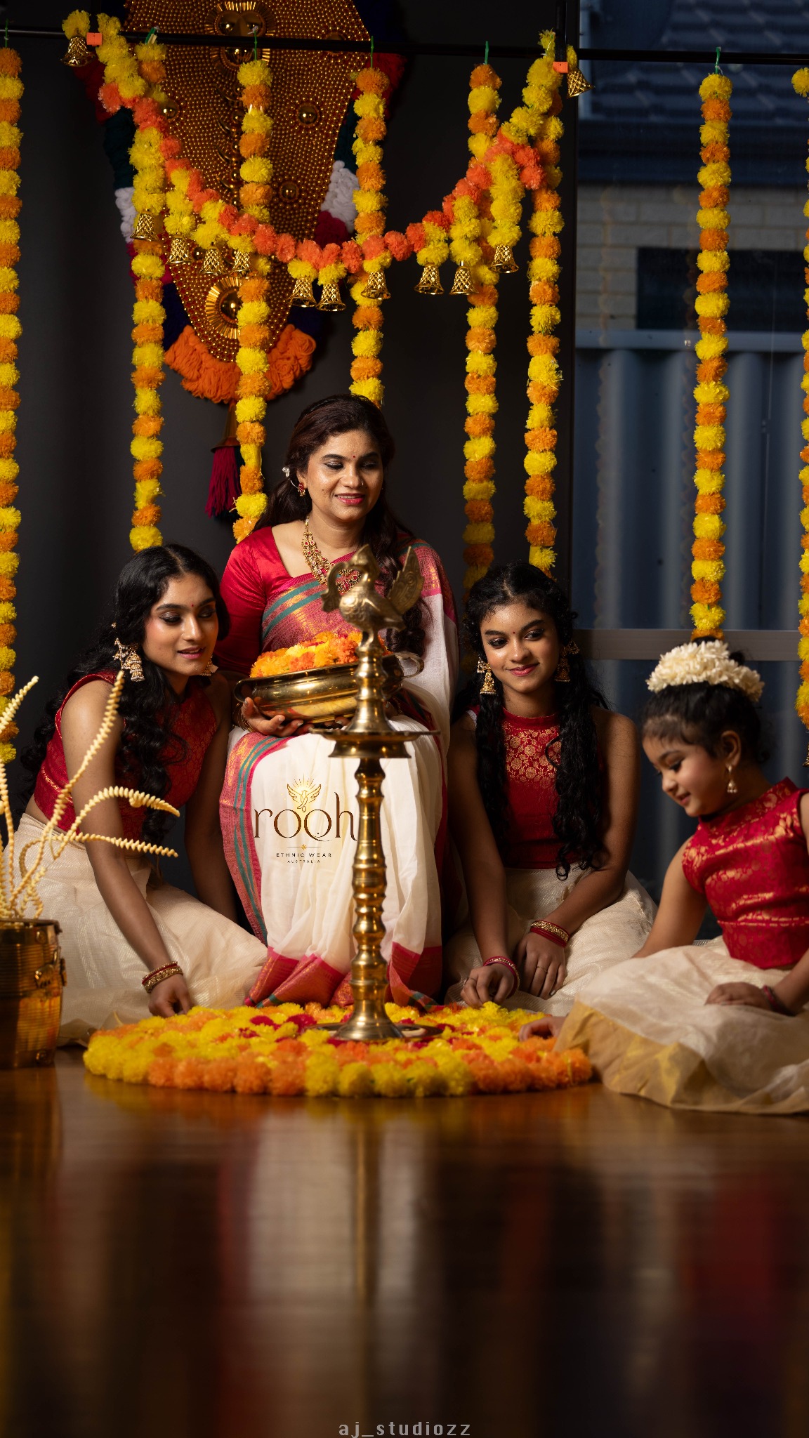 Onam ethnic-wear portrait around a flower pookalam and traditional lamp